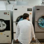 A Man in White Long Sleeves Sitting Beside the Washing Machine